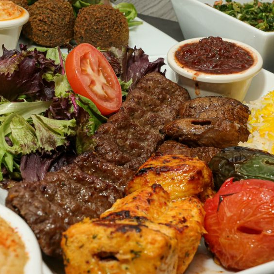 A Kookoo Cafe platter with grilled meats, falafel, salad, rice, and dipping sauces.